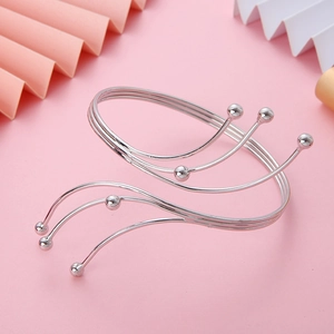 Detail of layered silver metal arm cuff featuring sleek wavy lines and ball ends