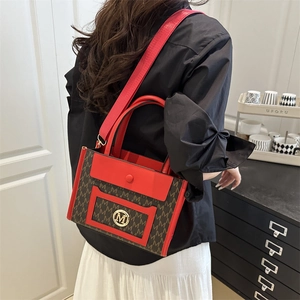 Large tote bag with red and brown letter prints, featuring a golden M logo and wide strap