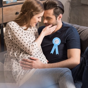 Blue Daddy to be ribbon badge for baby shower party worn by expecting father on sofa