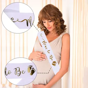 Detail of white satin Mommy to Be sash with gold foil font and cute footprint design