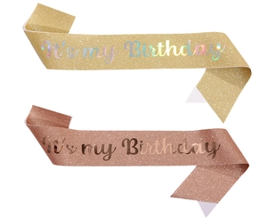 Detail of glitter birthday sash set in gold and rose gold with holographic lettering