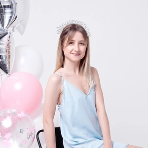 Silver Happy Birthday headband with rhinestones worn by a smiling woman at a party