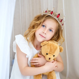 Detailed view of vintage gold baroque crown with red crystals on a young girl model