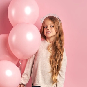 Sparkling silver rhinestone Happy Birthday headband worn by a girl against pink balloons