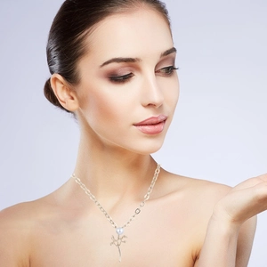Detail showing a nature-inspired leaf branch pendant with white pearl on a long necklace