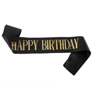 Detail of black glitter fabric birthday sash with shiny gold Happy Birthday text