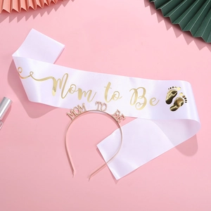 Draufsicht auf Mom to Be Schärpe aus Satin und Roségold-Haarreif auf rosa Hintergrund