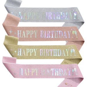 Detail of glitter fabric birthday sashes in 4 colors with holographic text and pin