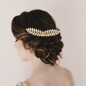 Detail of golden leaf bridal hair comb accessory styled in a sophisticated updo