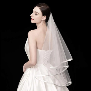 Elegant white double-layered bridal veil with satin ribbon edge on model against black background