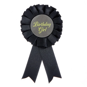 Detail of black pleated satin ribbon badge featuring yellow Birthday Girl script