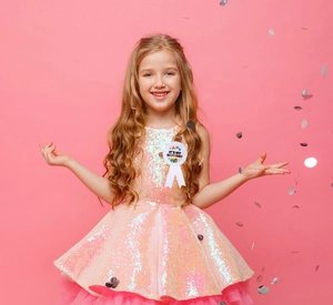 Détail du badge d'anniversaire en satin blanc et robe de fête rose à paillettes