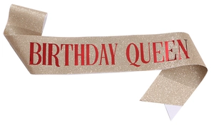 Close-up of glittery champagne gold sash with red metallic Birthday Queen text