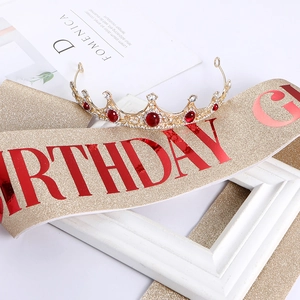 Detail of glitter Birthday Girl sash and gold tiara with red rhinestones for parties