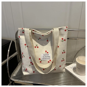 Détail du sac cabas en velours côtelé avec motif cerise et étiquette sur étagère