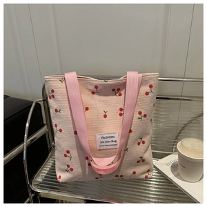 Détail du sac cabas en velours côtelé rose avec motif cerise sur étagère