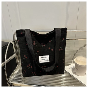 Détail d'un cabas en velours côtelé noir avec imprimé cerise et étiquette en toile