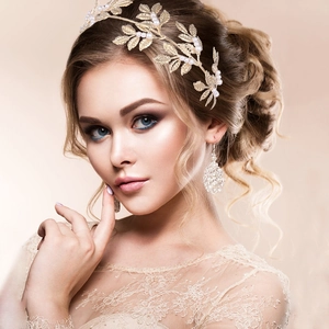 Detail of golden leaf bridal headband with white pearls and crystal drop earrings