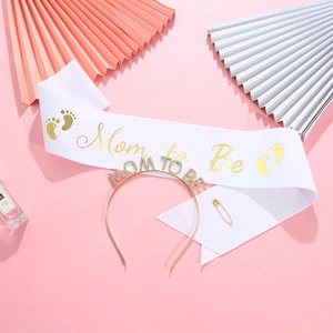 Mom to Be party set with gold rhinestone headband and white satin sash on pink background