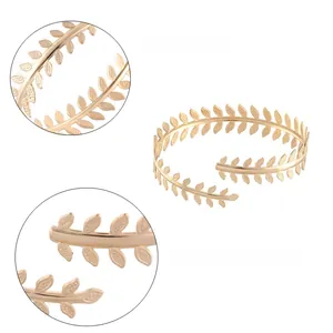 Close-up detail of golden laurel leaf texture on vintage style metal arm bracelet