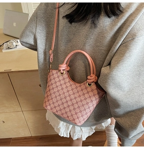 Vue latérale du sac seau rose à monogramme avec poignées rondes et détails dorés