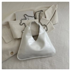 Detailed macro view of ivory glossy patent leather handbag with silver chain strap
