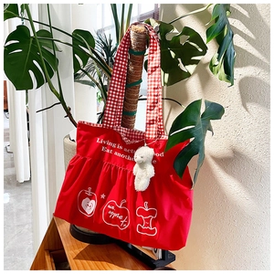 Detail of red pleated tote bag with apple print, checkered handles and bear keychain