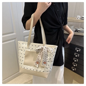 Détail d'un sac cabas plissé crème avec poche en cuir et ruban en soie décoratif