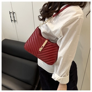 Détail du sac bandoulière matelassé bordeaux avec chaîne dorée porté par un mannequin