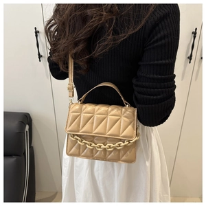 Quilted crossbody bag with chunky chain detail shown on a model in a stylish indoor setting