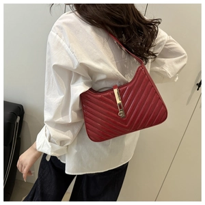 Détail du sac sous le bras en cuir verni rouge avec coutures en V et fermoir doré