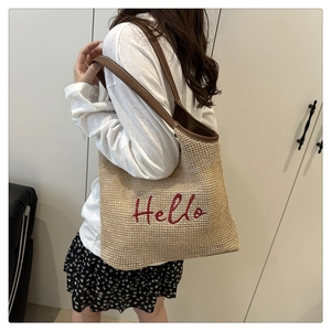 Dettaglio della grande borsa tote intrecciata con ricamo Hello rosso e manici in pelle