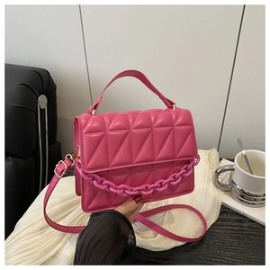 Detailed close-up of fuchsia quilted handbag with acrylic chain and glossy leather texture