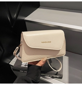 Close-up of off-white crossbody bag featuring a textured flap and golden fashion logo