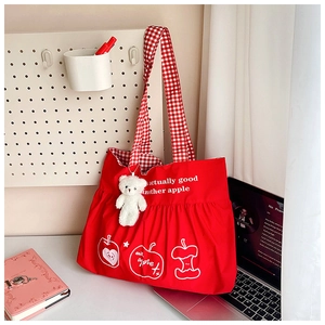 Detail of red canvas travel tote with white pleated ruffles, apple print, and bear charm