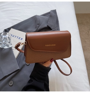 Close-up of brown leather and woven texture mix crossbody bag with gold lettering