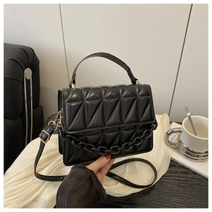 Detail of black quilted crossbody bag with glossy acrylic chain and elegant top handle