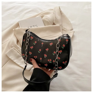 Close-up of black baguette bag with cherry print and silver chain strap handle