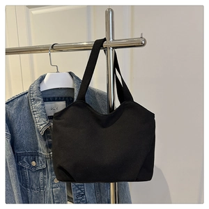 Detail of minimalist black canvas tote bag with wide straps and smooth fabric texture