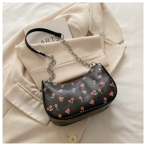 Detail of cherry print pattern and silver chain strap on a black leather hobo bag