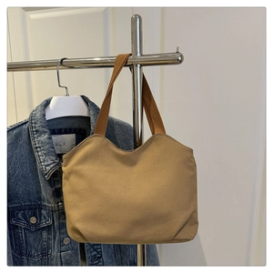 Detail of minimalist khaki canvas tote bag hanging next to a blue denim jacket