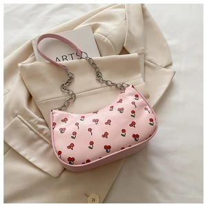 Close-up of pink crescent bag with red cherry prints and silver chain shoulder strap