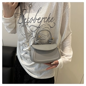 Detail of grey mini crossbody bag with knot handle and adjustable strap on model