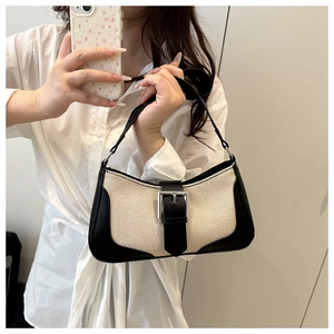 Detail of a french linen patchwork baguette bag with black leather trim and metal buckle