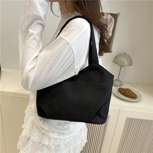 Minimalist black canvas tote bag for women showing sleek side view and woven shoulder straps