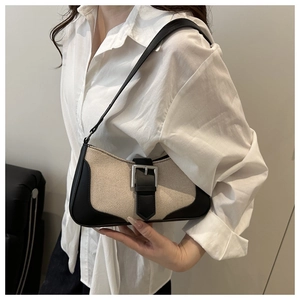 Close-up of retro off-white canvas underarm bag with black leather trim and buckle