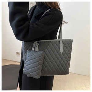 Gros plan d'un cabas matelassé gris avec surpiqûres losanges et petite pochette
