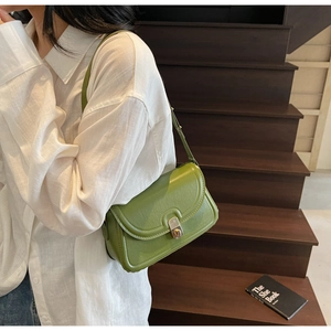 Détail du sac bandoulière en cuir vert herbe avec fermoir métallique sur un mannequin