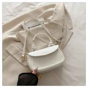 Macro detail of white PU leather crossbody bag featuring a unique knotted top handle design
