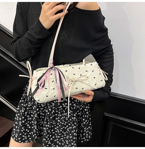 Detail einer weißen Stepptasche mit schwarzen Schleifenmustern und großer Seidenschleife
